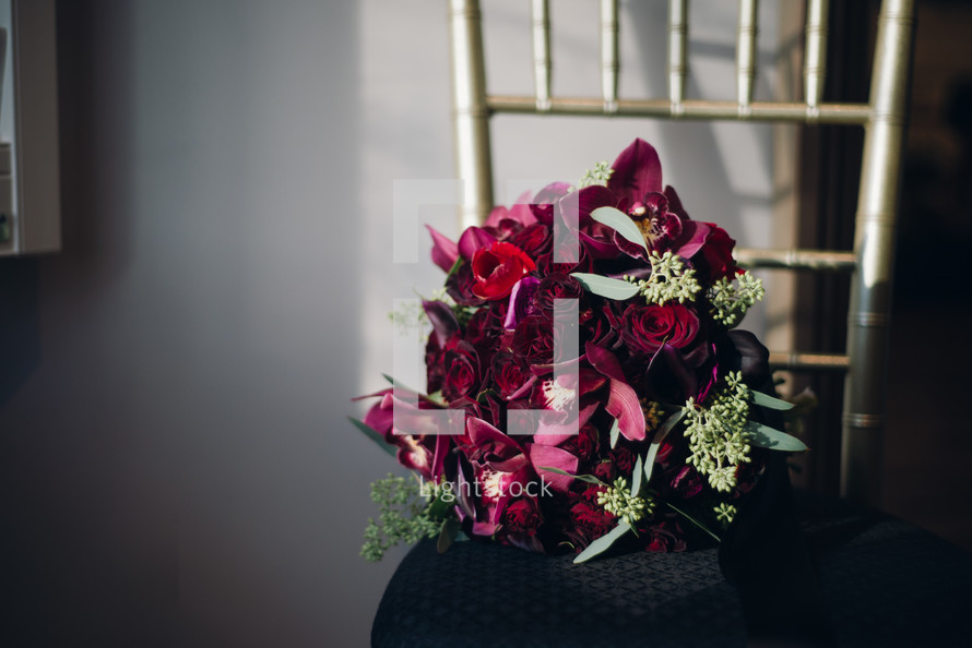 magenta roses in a bouquet in a chair at a wedding 