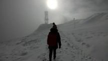 Girl running on a snowy mountain within fog - follow cam