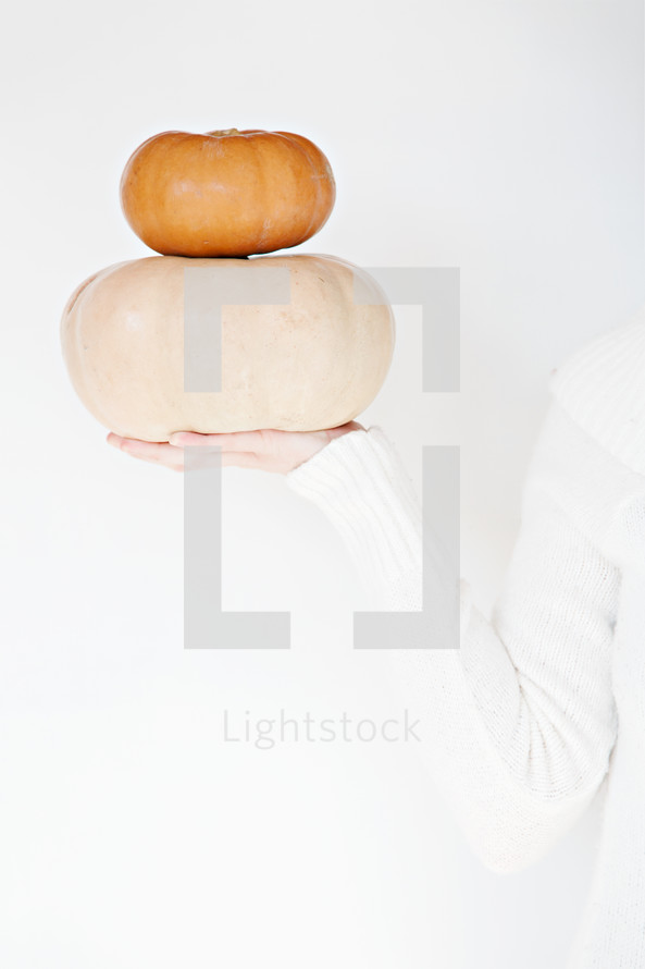 woman holding out stacked pumpkins 