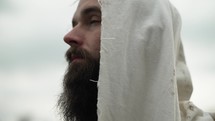 Actor portraying Jesus Christ, bible prophet or disciple in white tunic looking to God in heaven in prayer, worship and contemplation.
