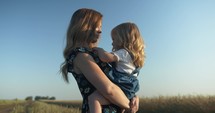 Mother holding and kissing her daughter.