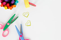 scissors, markers, and paper clips on a white background 