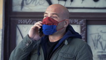 man talking on a cellphone outdoors wearing a face mask 