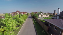 Neighborhood Houses Street Flying over Residential Area with many houses with pools and green grass gardens