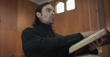 Young pastor in church with bible preaching, teaching sermon to congregation in Sunday morning worship service.