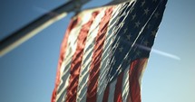 American flag blowing in wind in slow motion in light of sunset.