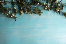branches and white berries on a blue wood background