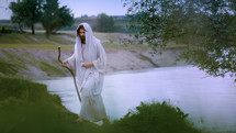 Jesus Christ walking alone near a Jordan River bank.
