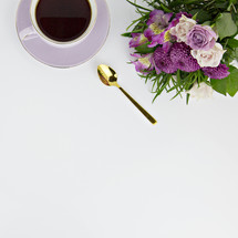 coffee cup, spoon, and purple flowers on a white background 