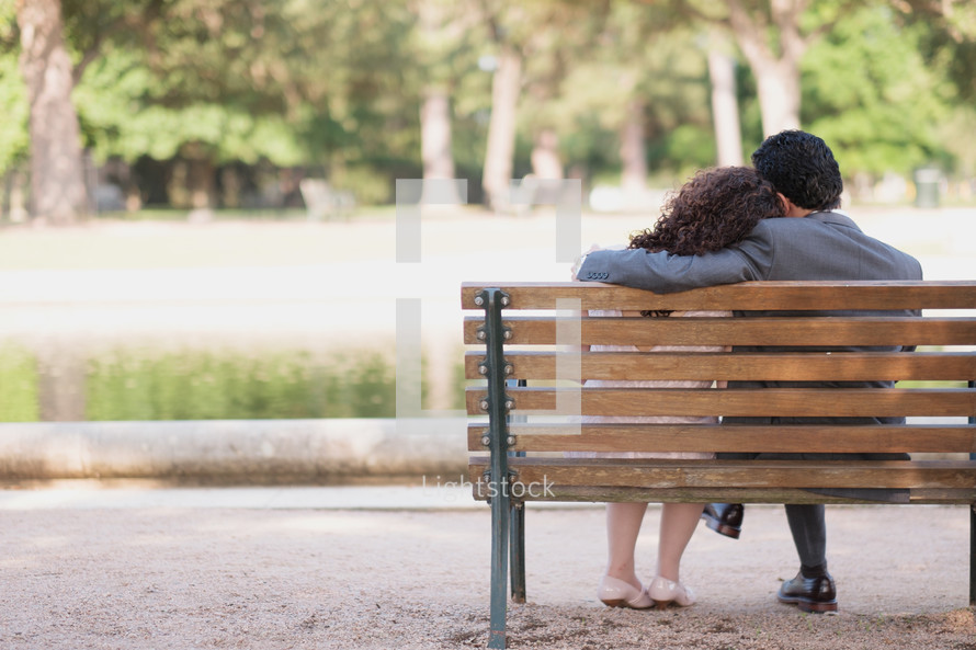 couple snuggling on a park bench 