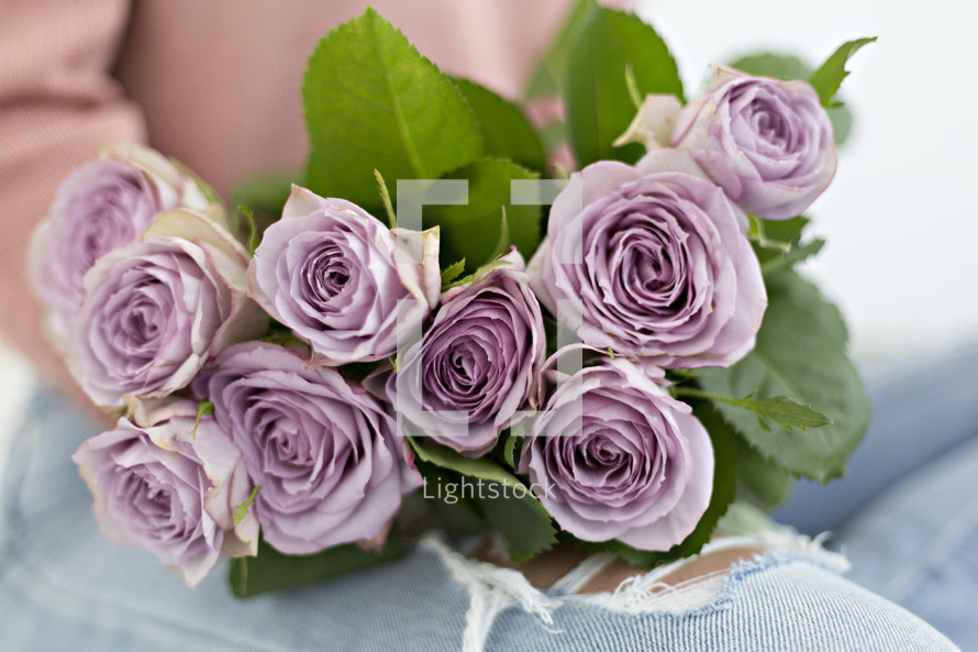 a woman with a bouquet of purple roses in her lap