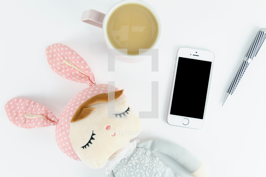 toy, coffee mug, iPhone, and pen 