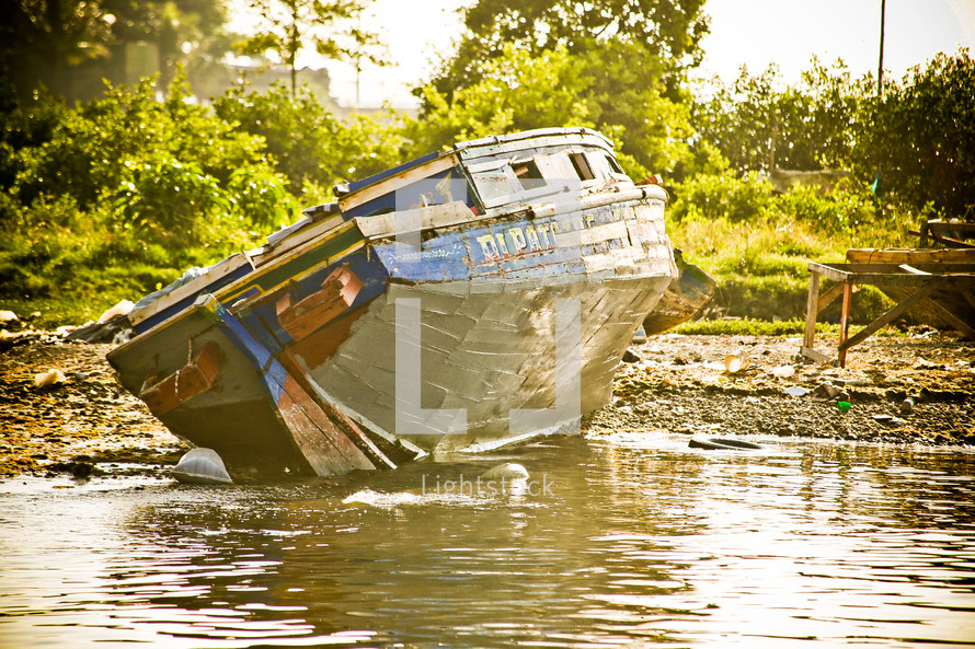 Weathered boat stuck in the mud of a lake.