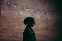 woman standing under a string of lights