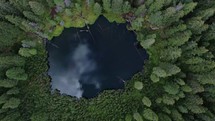 Aerial video of a remote glacial lakes in the mountains of Romania surrounded by dense pine forest