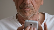 Close up of an older man using a cell phone.