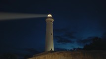 Lighthouse tower in the night with beam light