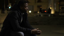 a man in a city at night praying 