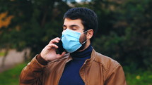 a man wearing a face mask talking on a cellphone 