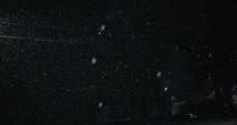 Slow motion snow at night in front of black backdrop, Snowflakes falling in slow motion during winter snow storm at nighttime.