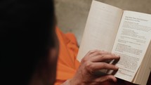 A man in prison reading a bible.