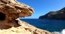 Waves hitting the rocky coast of Majorca, sunny day, in Balearic islands, Spain