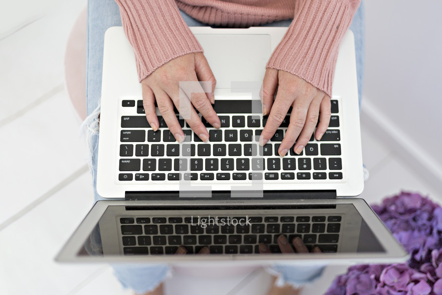 a woman typing with a laptop computer in her lap 