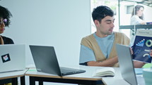 Young gen Z man holding paper with business graphs and explaining financial data to team of colleagues on a meeting in modern coworking room
