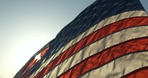 Sunset light shines on American, USA flag blowing in the wind in slow motion on 4th of July, Independence Day.