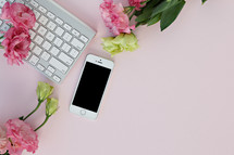 pink carnations, computer keyboard, and cellphone on desk 