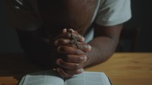African American Man Holding Cross and Praying Deeply with Bible