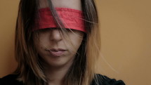 Woman with a red blindfold covering her eyes.