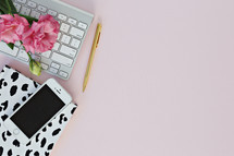 cellphone, notebook, keyboard, and pen on a pink background 