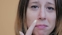Woman touching a blemish on her face.
