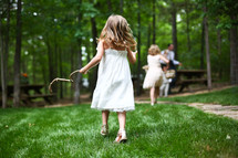 little girl running holding a stick in the park