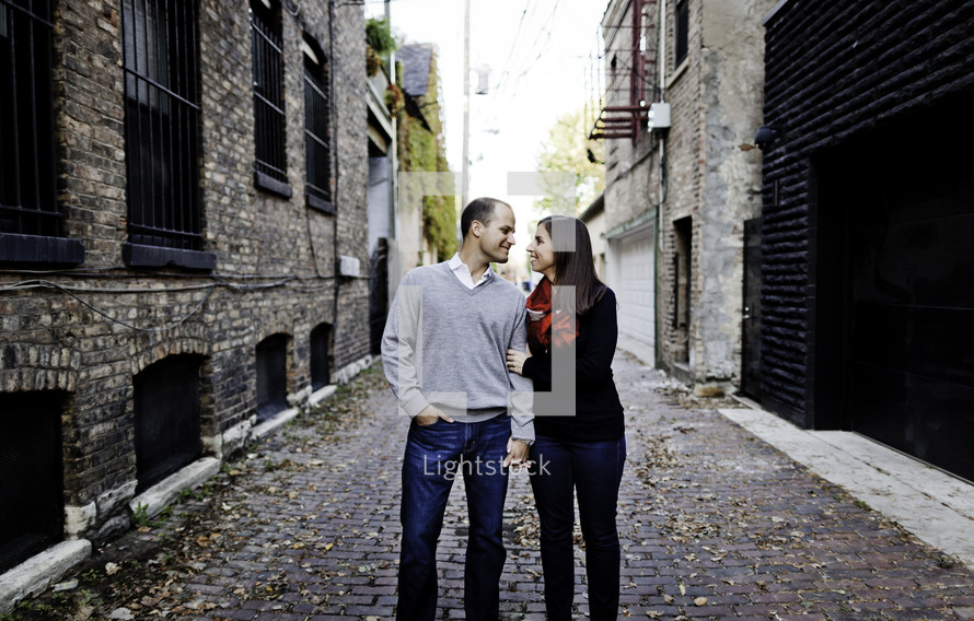 A happy couple stands in a cobble-stoned alley