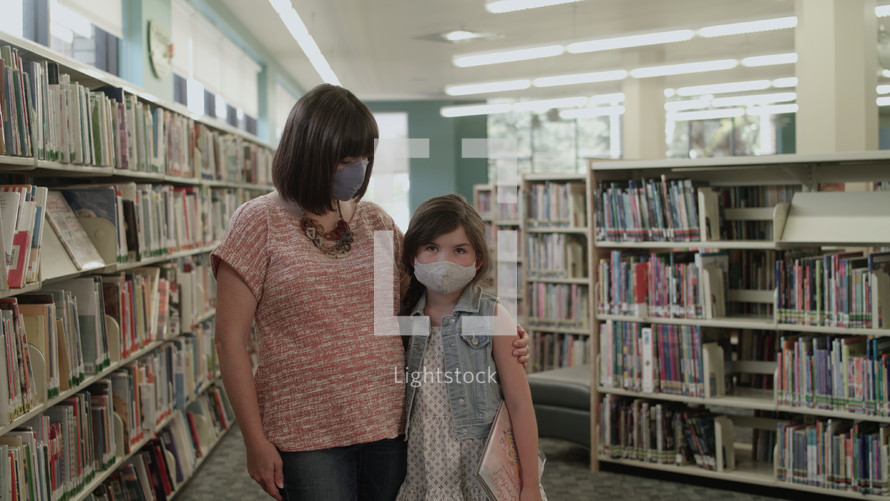 a mother and daughter at the library wearing face masks 