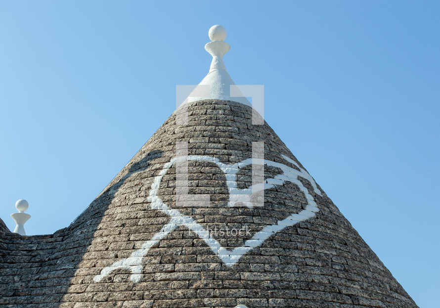 White heart painted on a traditional trulli roof in alberobello, a small town in puglia, italy, famous for its particular whitewashed conical roof houses