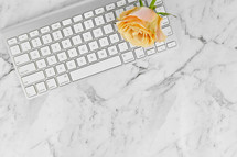 computer keyboard, and yellow roses on a marbled background 