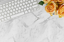 computer keyboard, and yellow roses on a marbled background 
