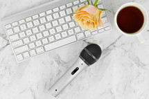cup of tea, microphone, computer keyboard, and yellow roses on a marbled background 