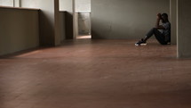 a young man sitting on the floor alone in an empty room 