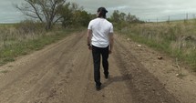 Young man walking on unpaved, dirt road on summer day explore, hiking, worshipping and praying. Lifestyle, worship and prayer concept.