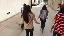 group of young adults walking and talking in an alley 
