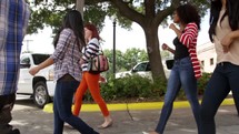 a small group of young adults walking down a sidewalk 