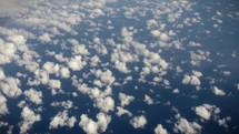 View of earth, ocean and clouds from airplane window while flying in cinematic slow motion.