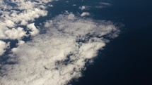 View of planet earth, ocean and clouds from airplane window while flying in cinematic slow motion.