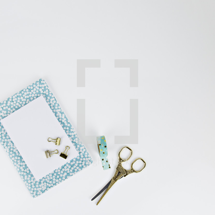 clips, tape, scissors, white paper, and floral planner 