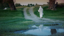 Jesus as the Eternal Pilgrim leaves on a muddy road at night.
