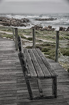 wood bench on a boardwalk overlooking the ocean 